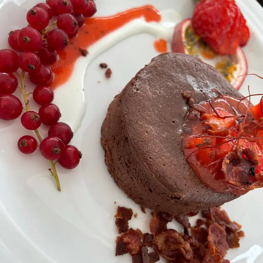 Angerichteter Lava Cake mit Johannisbeeren, Himbeeren und Fruchtspiegel