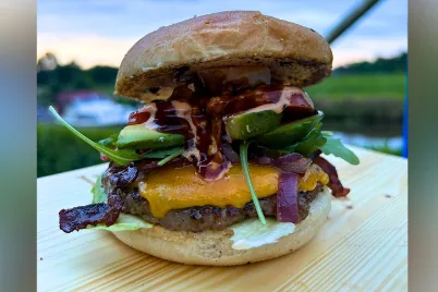 Saftiger Burger mit Spiegelei, Käse und Speck auf dunklem Untergrund