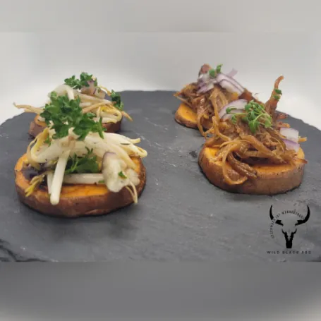 Zwei belegte BBQ-Bites mit Pulled Pork und Coleslaw auf einer Schieferplatte