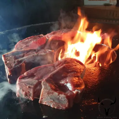 Zwei Steaks garen über offenem Feuer in einer Feuerschale